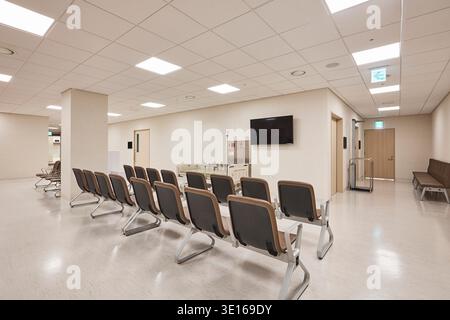 Open waiting area with rows of chairs in a modern hospital department. Stock Photo