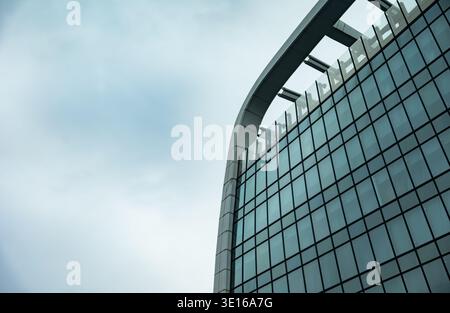 Modern glass facade curving against clear sky showcasing contemporary architecture Stock Photo