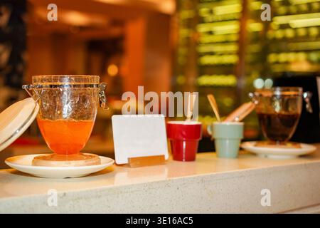 Oriental buffet bar offering various sauces and condiments in glass jars, ceramic cups with spoons, ready for diners to enhance their meal experience Stock Photo