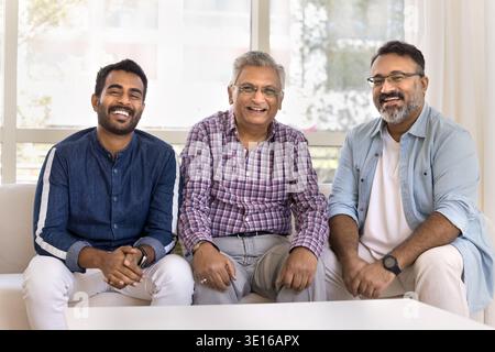 Three Indian men of different generations sitting together on sofa Stock Photo
