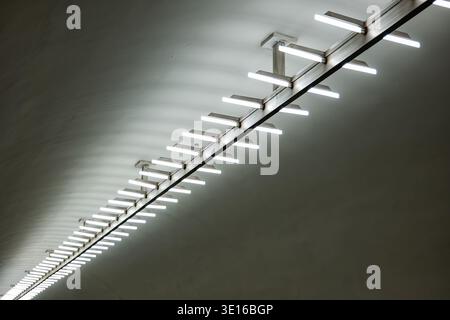Long line of fluorescent lights illuminating a concrete architectural interior Stock Photo
