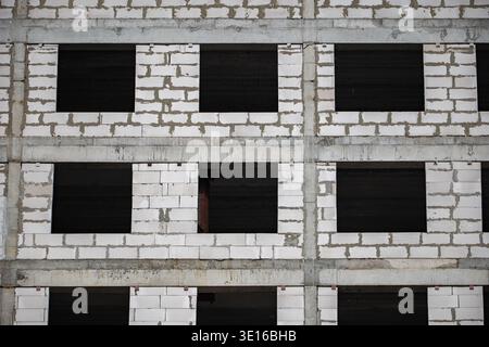 Building framework with white concrete blocks and dark empty window openings Stock Photo