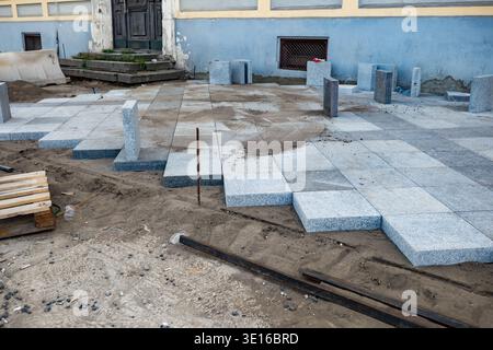 Urban paving installation, workers laying granite cobblestone on street ground Stock Photo