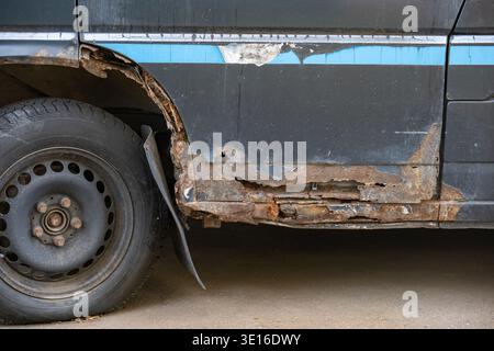 Car body rusting and decaying, showing corrosion on old metal vehicle door and wheel arch Stock Photo