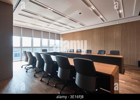 Modern boardroom with a long wood table and black chairs. Stock Photo