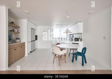 Bright minimalist kitchen and dining room with white cabinetry. Stock Photo