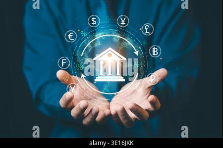 Businessman hands holding glowing bank icon with global currency symbols and world map, international banking and global financial exchange concept. Stock Photo