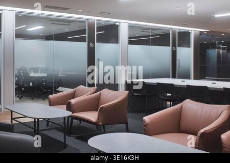 Moody office lounge with soft seating behind glass partitions. Stock Photo