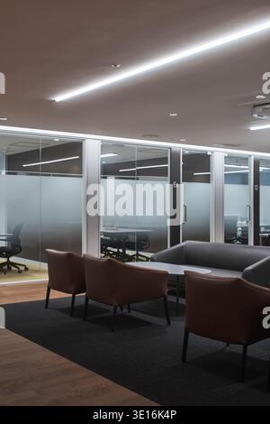 Moody office lounge with soft seating behind glass partitions. Stock Photo