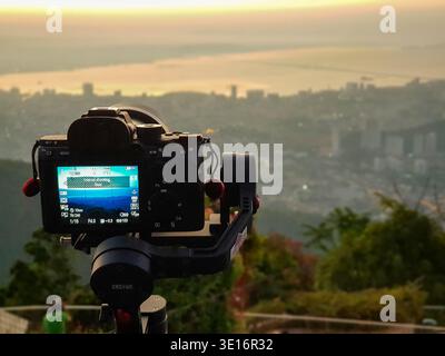 Penang, Malaysia – January 25, 2020: A camera mounted on a gimbal faces the city skyline and coastline at sunset. Stock Photo