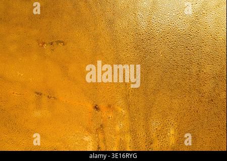 Condensation on yellow glass creates abstract wet texture, droplets sparkling under diffused light, closeup detail showing natural water pattern, mode Stock Photo