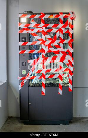 One Broken Vending Machine with Shattered Glass and Red Tape After Vandalism Theft Crime in Switzerland. Stock Photo
