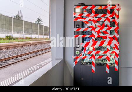 One Broken Vending Machine with Red Warning Tape and Shattered Glass at Train Station After Vandalism in Switzerland. Stock Photo