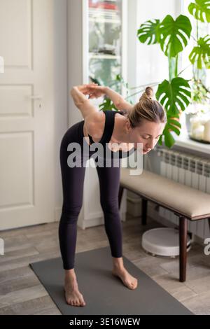 Focused mature woman doing fitness routine training at home, physical activity for stress relief. Stock Photo