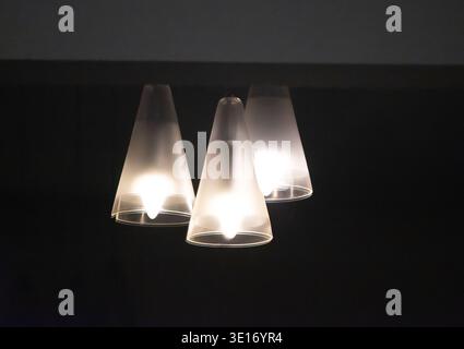 Reflection of three white hanging electric lights in a dark window. Black and white. Copy space. White lights on black background. Australia. Stock Photo