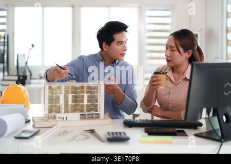 Adult Asian architects collaborating on a building model design in their office discussing innovative project plans teamwork brainstorming professiona Stock Photo