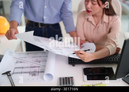 Asian adult male female professionals discuss architectural blueprints engineering project plan office setting team collaboration design development c Stock Photo