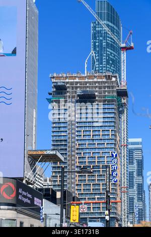 High rise building under construction with tower crane rising above a downtown city street. Stock Photo