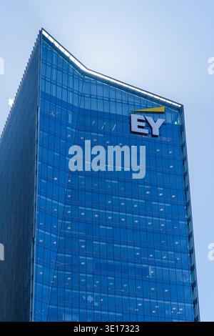Glass office tower with EY logo on the facade against a clear blue sky. Stock Photo