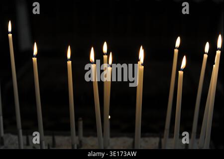 Burning candles in the dark room or nave of a church Stock Photo