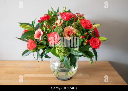 Bright Coral Rose Bouquet In A Glass Vase On Wooden Table With Greenery And Buds Stock Photo