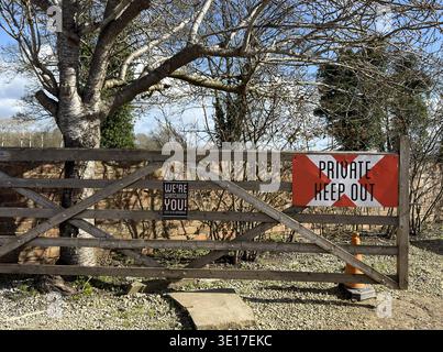 Wooden countryside gate with private property warning signs reading “Private Keep Out” and “We’re watching you”, illustrating security, trespass and r Stock Photo