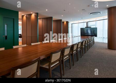 Long conference table in a warm timber lined boardroom. Stock Photo