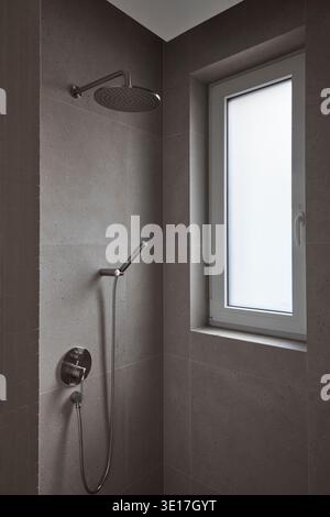 Dark tiled shower room with small window. Stock Photo