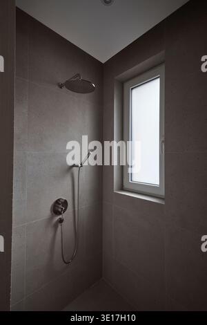 Dark tiled shower room with small window. Stock Photo