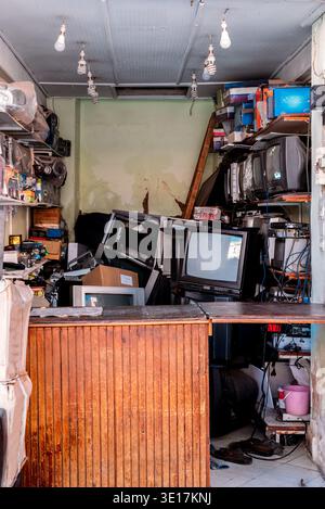 A cluttered workshop filled with vintage televisions, electronics, and various tools. The room is in disarray, showcasing outdated technology amidst a Stock Photo