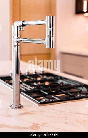 Close-up view of a luxury kitchen featuring a modern chrome faucet and elegant marble countertop. The sleek design highlights refined taste and contem Stock Photo
