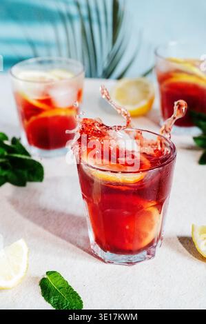 A dynamic image capturing the vibrant splash of red wine in a glass, accented with citrus slices. Perfectly embodies a refreshing summer drink, surrou Stock Photo