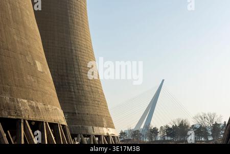 A landscape view showcasing industrial cooling towers alongside a modern cable-stayed bridge under a clear sky, symbolizing new life and transformatio Stock Photo