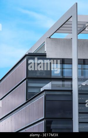Sleek modern office tower with reflective glass facade in bustling business district; epitomizes contemporary urban architecture and innovation agains Stock Photo