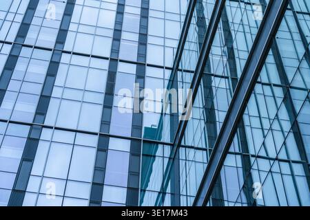 A striking view of a modern glass office building showcasing its sleek blue facade. The reflective surface captures the essence of contemporary corpor Stock Photo