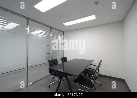 Small meeting room with black table and chairs. Stock Photo