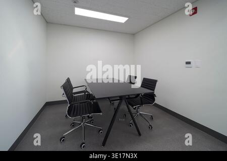 Small meeting room with black table and chairs. Stock Photo