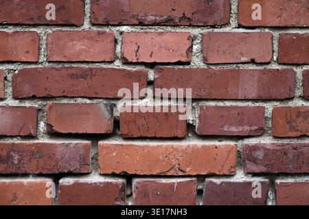 Texture of an old red brick wall with visible mortar and weathered surface. Close-up of traditional masonry with rustic character and scratches Stock Photo