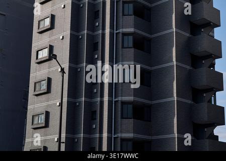 Dark apartment facade with deep balcony shadows and vertical rhythm. Stock Photo