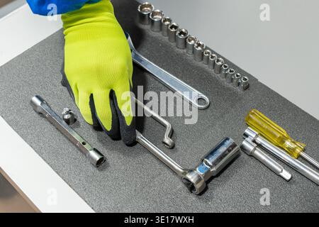 High angle shot of an unrecognizable repair man's hands grabbing a tool from his tool Stock Photo