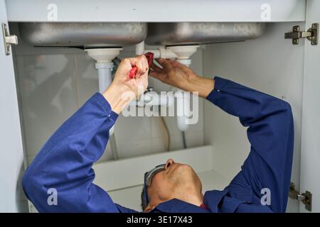Latin American plumber fixing a pipe in the kitchen of a house - home improvement concepts Stock Photo