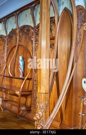 Intricate Art Nouveau wooden interior featuring flowing curved lines and elaborate floral carvings. The built-in cabinetry showcases sinuous organic Stock Photo