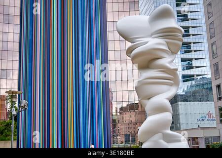 A vibrant urban scene featuring two distinct modern art installations set against contemporary glass skyscrapers in Paris, France. On the left,... Stock Photo