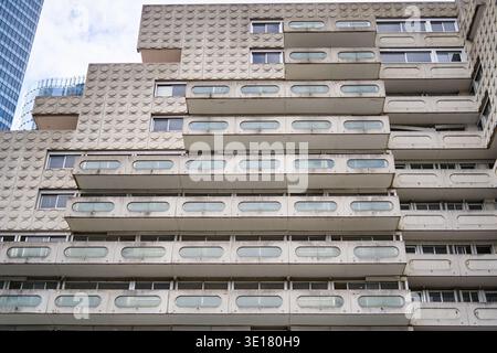 Close-up view of a brutalist concrete residential building facade featuring repetitive geometric patterns and horizontal balconies with... Stock Photo