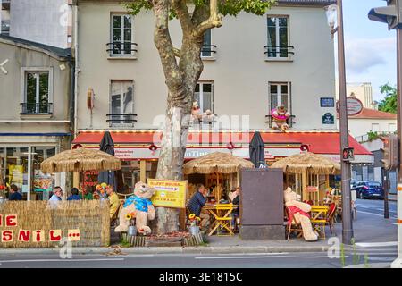 A vibrant street scene featuring a charming Parisian café corner adorned with whimsical giant teddy bear decorations. The outdoor terrace... Stock Photo