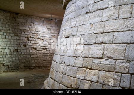 Ancient stone walls constructed from irregular limestone blocks dominate this underground interior space in Paris, France. The foreground... Stock Photo