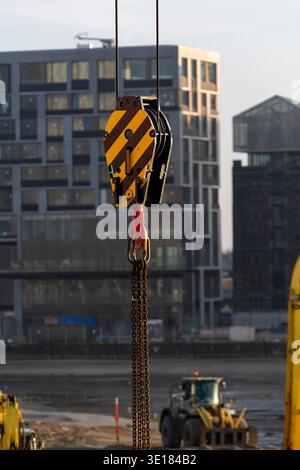 Close up of yellow (industrial) heavy-duty crane hook block, single sheave (pulley) model for heavy lifting operations on construction site with build Stock Photo
