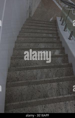 Modern handrails frame the ascent with clean lines. Wall meets staircase in minimalist architectural style Stock Photo