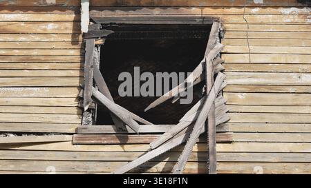 Charred window frame and broken pieces of wood on a damaged house after a fire Stock Photo