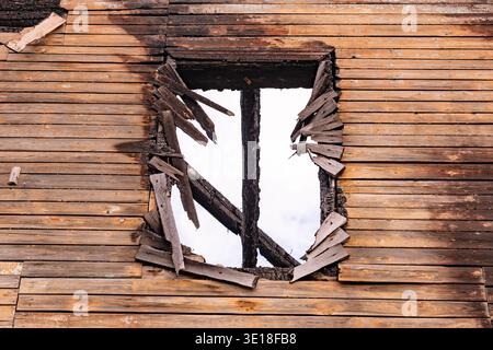 Burnt house facade showing fire damage and destruction through a broken window Stock Photo